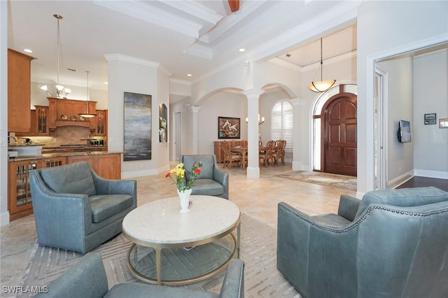 living room with a high ceiling, ornate columns, and crown molding