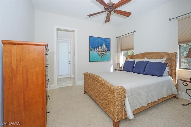 bedroom featuring ceiling fan, light colored carpet, and ensuite bath