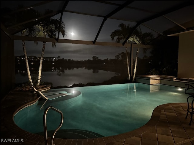 pool at twilight with a water view and an in ground hot tub