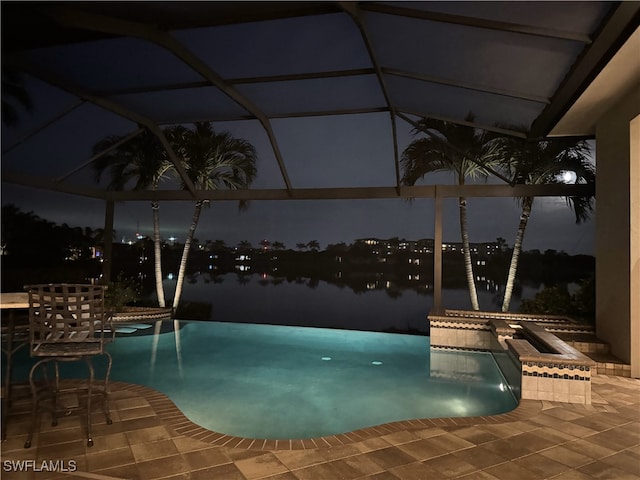 pool at twilight featuring glass enclosure, an in ground hot tub, a water view, and a patio