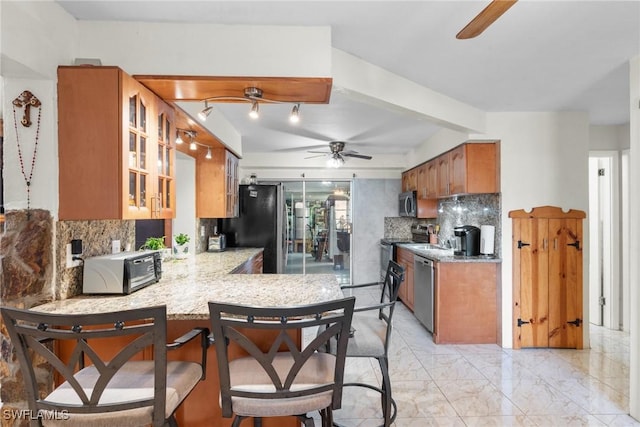 kitchen with decorative backsplash, appliances with stainless steel finishes, kitchen peninsula, and ceiling fan