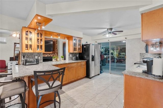 kitchen with tasteful backsplash, ceiling fan, kitchen peninsula, stainless steel fridge with ice dispenser, and a kitchen breakfast bar