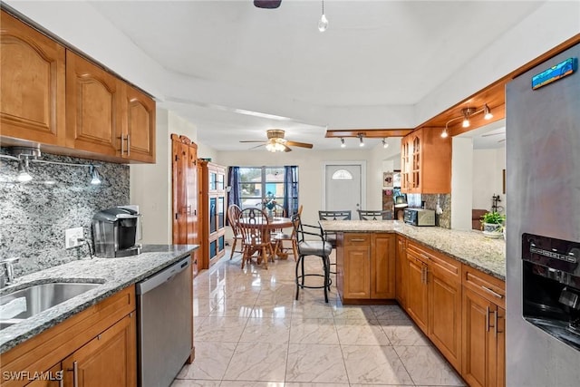 kitchen with a kitchen bar, kitchen peninsula, stainless steel appliances, decorative backsplash, and light stone countertops