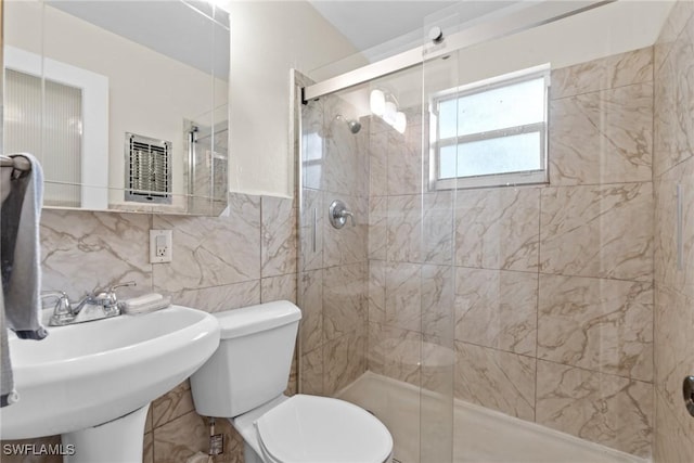 bathroom featuring toilet, tile walls, backsplash, and a shower with door