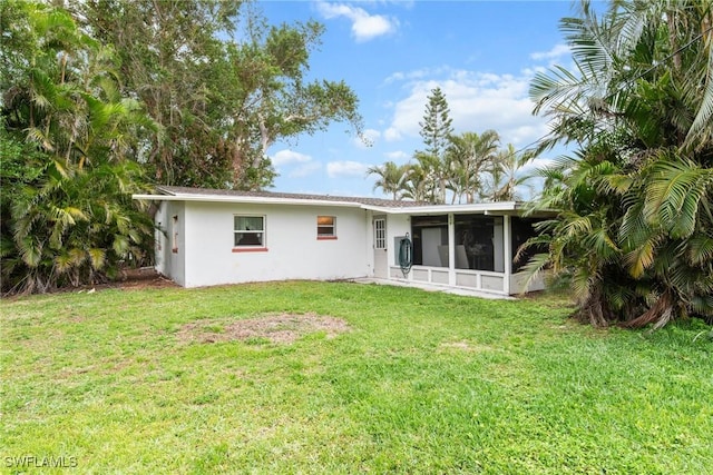 rear view of house featuring a sunroom and a yard