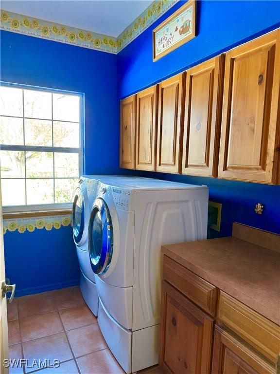 clothes washing area with cabinets, independent washer and dryer, and light tile patterned floors