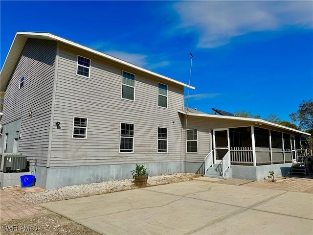 rear view of house with cooling unit and a sunroom