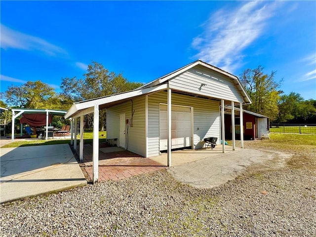 view of home's exterior with a garage, a carport, and an outdoor structure