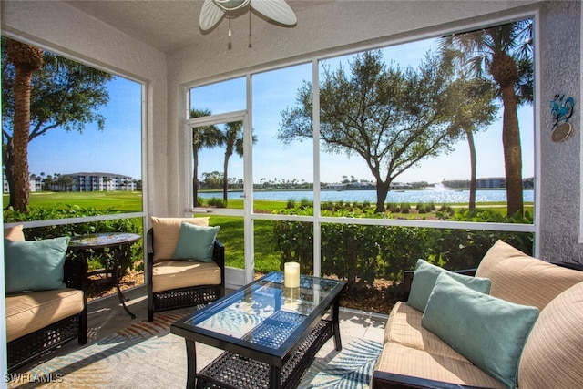 sunroom with ceiling fan and a water view