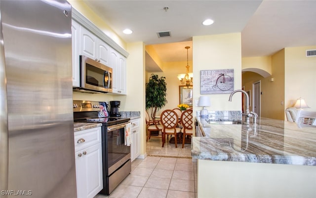 kitchen with sink, light tile patterned floors, appliances with stainless steel finishes, light stone counters, and white cabinetry