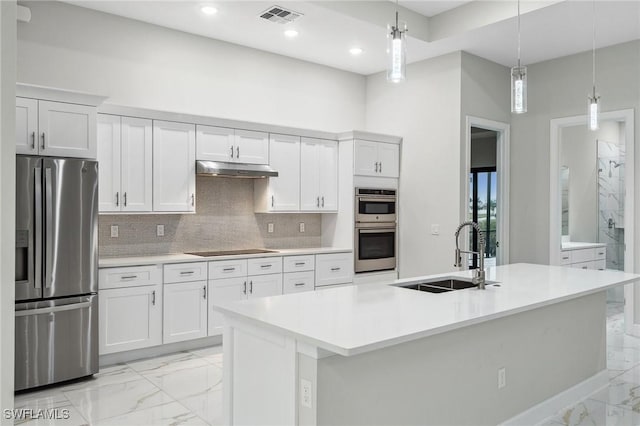 kitchen featuring an island with sink, decorative light fixtures, sink, appliances with stainless steel finishes, and white cabinets