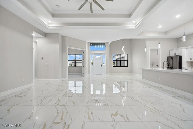 foyer featuring a raised ceiling, ceiling fan, crown molding, and sink