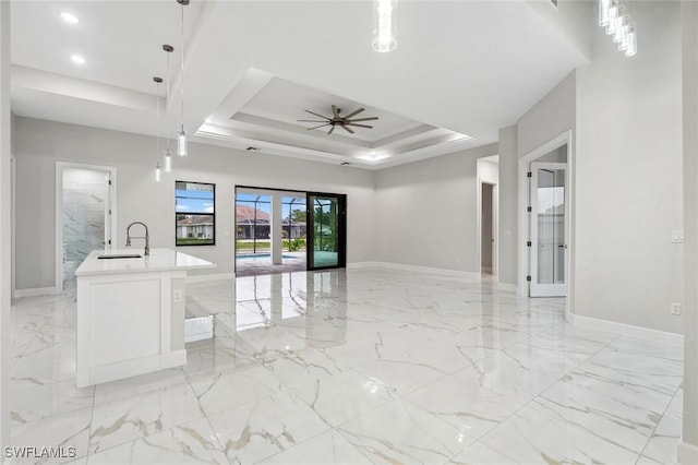 interior space with ceiling fan, sink, and a raised ceiling