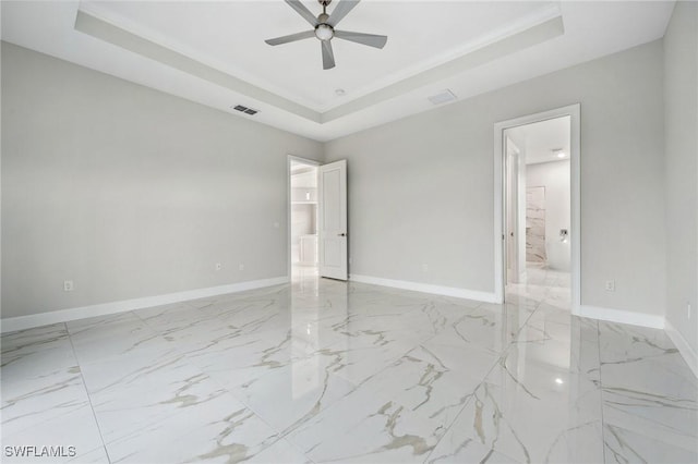 empty room with a raised ceiling and ceiling fan