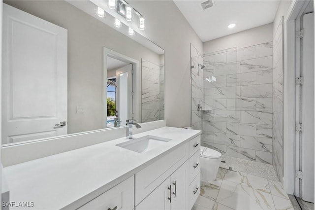 bathroom featuring toilet, tiled shower, and vanity