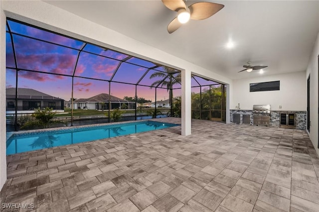 pool at dusk featuring a patio, area for grilling, ceiling fan, and glass enclosure