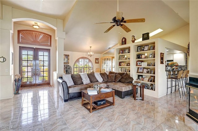 living room featuring ceiling fan with notable chandelier, built in shelves, high vaulted ceiling, and french doors