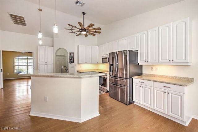 kitchen featuring ceiling fan, hanging light fixtures, stainless steel appliances, a kitchen island with sink, and white cabinets