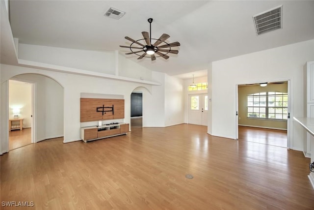 unfurnished living room featuring ceiling fan, french doors, light hardwood / wood-style floors, and vaulted ceiling