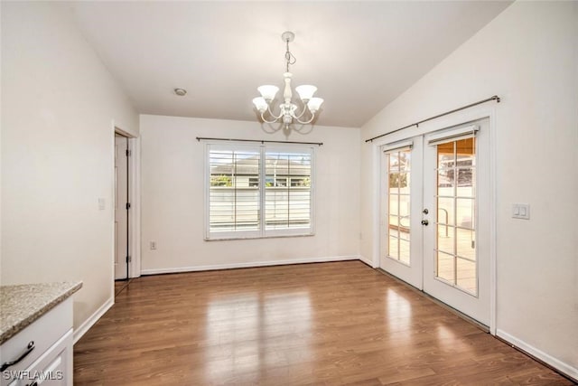 unfurnished dining area with french doors, vaulted ceiling, an inviting chandelier, and wood-type flooring