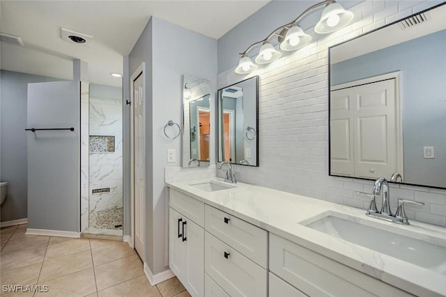 bathroom with a tile shower, backsplash, tile patterned floors, toilet, and vanity