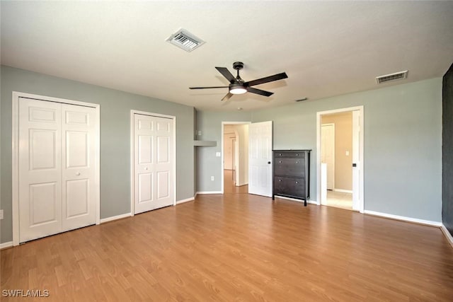 unfurnished bedroom with multiple closets, ceiling fan, and light wood-type flooring