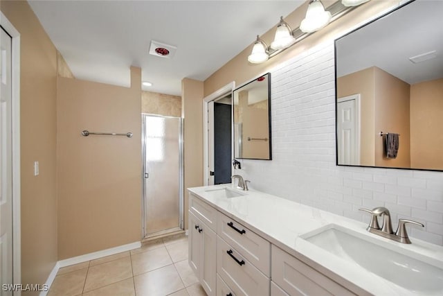 bathroom with tile patterned floors, vanity, a shower with door, and backsplash