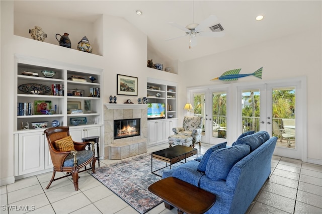 living room with a tile fireplace, french doors, light tile patterned floors, built in features, and ceiling fan