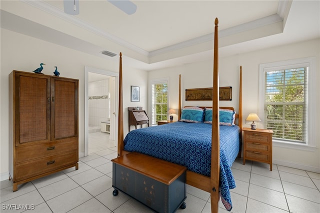 bedroom featuring ensuite bathroom, multiple windows, ceiling fan, and a tray ceiling