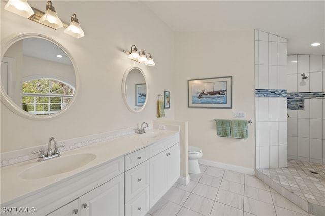 bathroom with toilet, a tile shower, vanity, and tile patterned floors