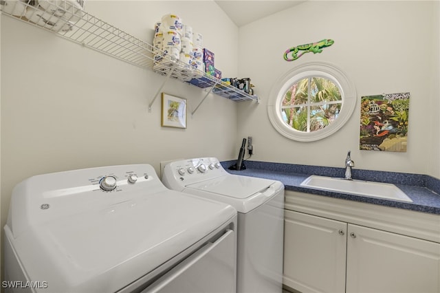 clothes washing area featuring sink, washing machine and clothes dryer, and cabinets