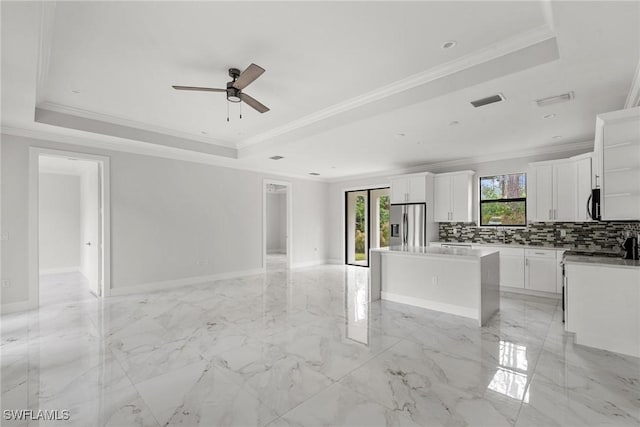 kitchen featuring a tray ceiling, a center island, and stainless steel appliances