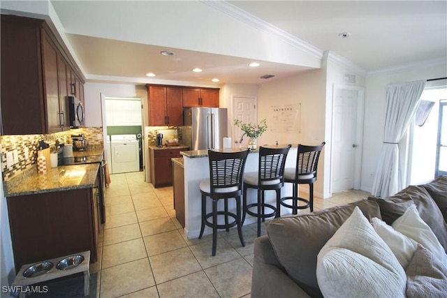 kitchen featuring stainless steel appliances, tasteful backsplash, independent washer and dryer, dark stone counters, and light tile patterned floors