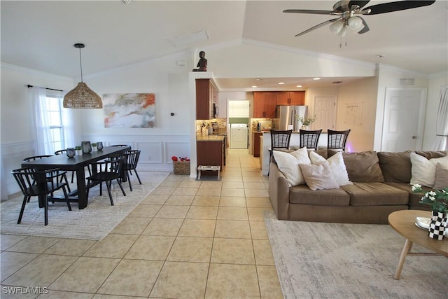 living room with lofted ceiling, ceiling fan, ornamental molding, light tile patterned floors, and washer / dryer