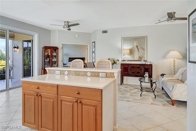 kitchen featuring ceiling fan, light tile patterned floors, and a center island