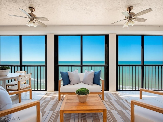 sunroom featuring ceiling fan, plenty of natural light, and a water view