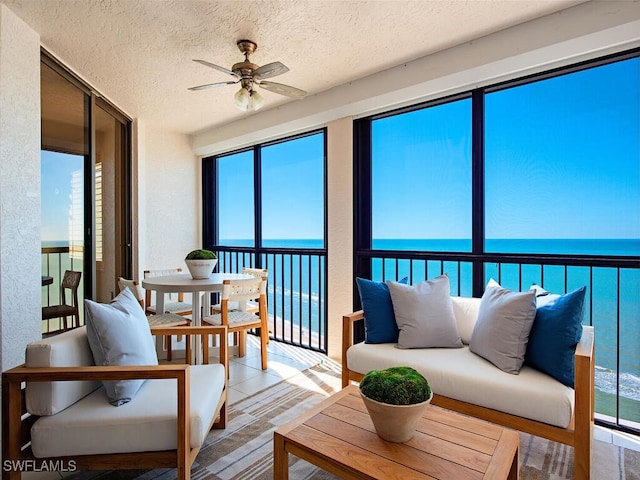 sunroom featuring ceiling fan and a water view