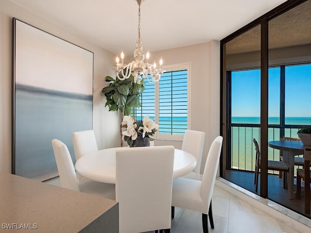 dining room featuring expansive windows, a water view, and a chandelier