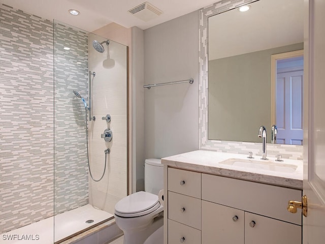 bathroom with tiled shower, vanity, and toilet