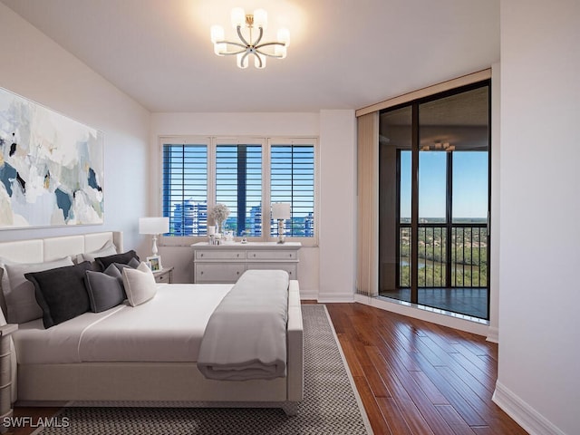 bedroom with dark hardwood / wood-style flooring, access to outside, and a notable chandelier