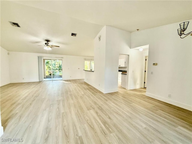 unfurnished living room featuring ceiling fan with notable chandelier and light hardwood / wood-style flooring