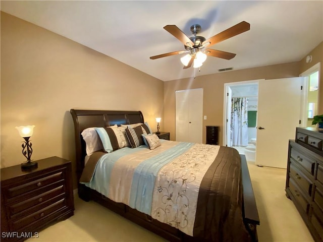 bedroom with light carpet, ensuite bath, and ceiling fan