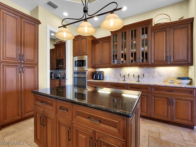 kitchen with a kitchen island, stainless steel appliances, dark stone counters, tasteful backsplash, and hanging light fixtures