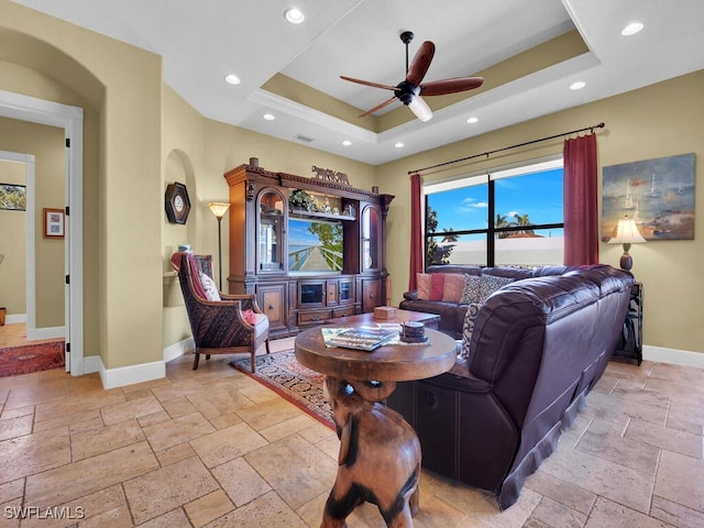 living room with ceiling fan and a tray ceiling