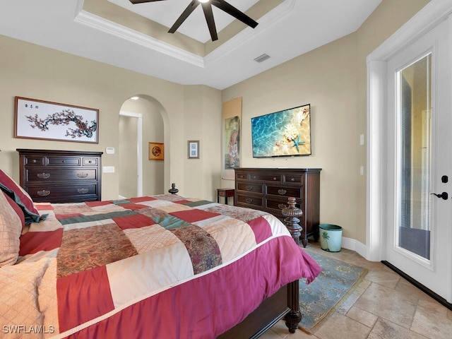 bedroom featuring ceiling fan, access to exterior, and a tray ceiling