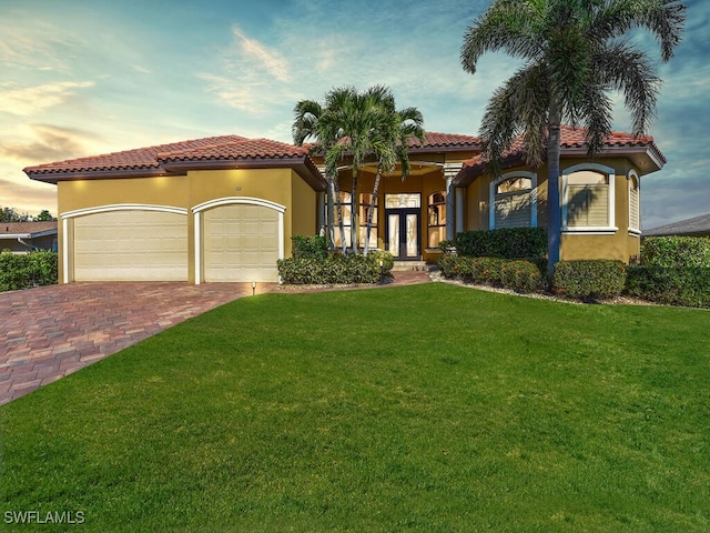 mediterranean / spanish house featuring a garage, a lawn, and french doors