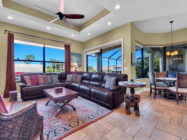 living room with ceiling fan with notable chandelier and a tray ceiling