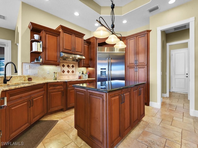 kitchen with decorative light fixtures, stainless steel built in fridge, tasteful backsplash, sink, and a notable chandelier