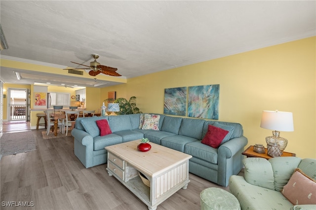 living room with crown molding, light hardwood / wood-style flooring, and ceiling fan