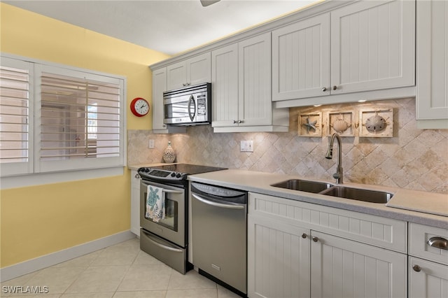 kitchen featuring sink, light tile patterned floors, decorative backsplash, and appliances with stainless steel finishes